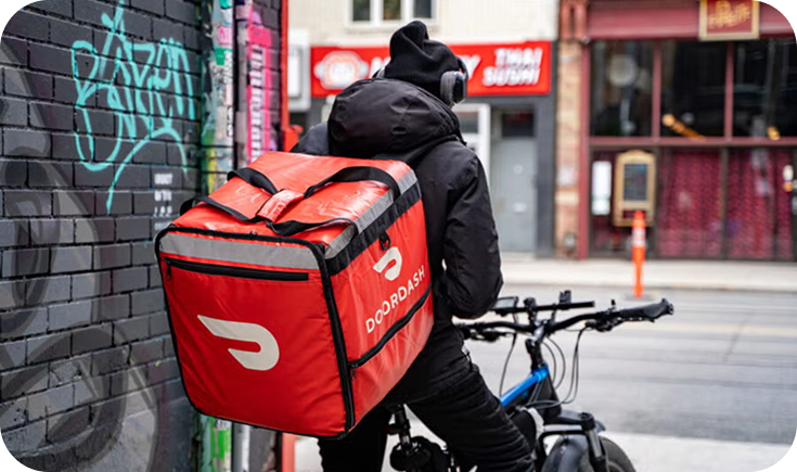 DoorDash courier with a red delivery bag and bicycle